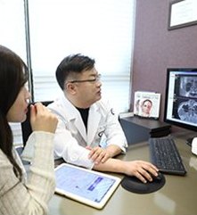 흰 가운 의사가 CT 화면을 보며 여성 환자와 상담